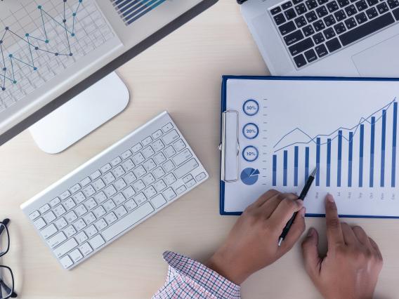 computer screen, keyboard and tablet displaying a business related graph