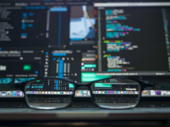 eyeglasses sitting on a table with blurred computer screens in the background